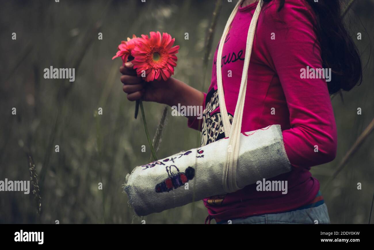 Ein Mädchen mit verletzter Hand, das Blumen hält und hereinkommt Natürliche Szene‌ Medizinische Schiene Hand Stockfoto