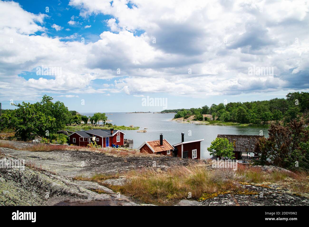 Schöner Sommertag im Archipel. Eine sehr malerische Aussicht mit roten Sommerferienhäusern direkt am Meer auf der Insel. Foto aufgenommen in Schweden. Stockfoto