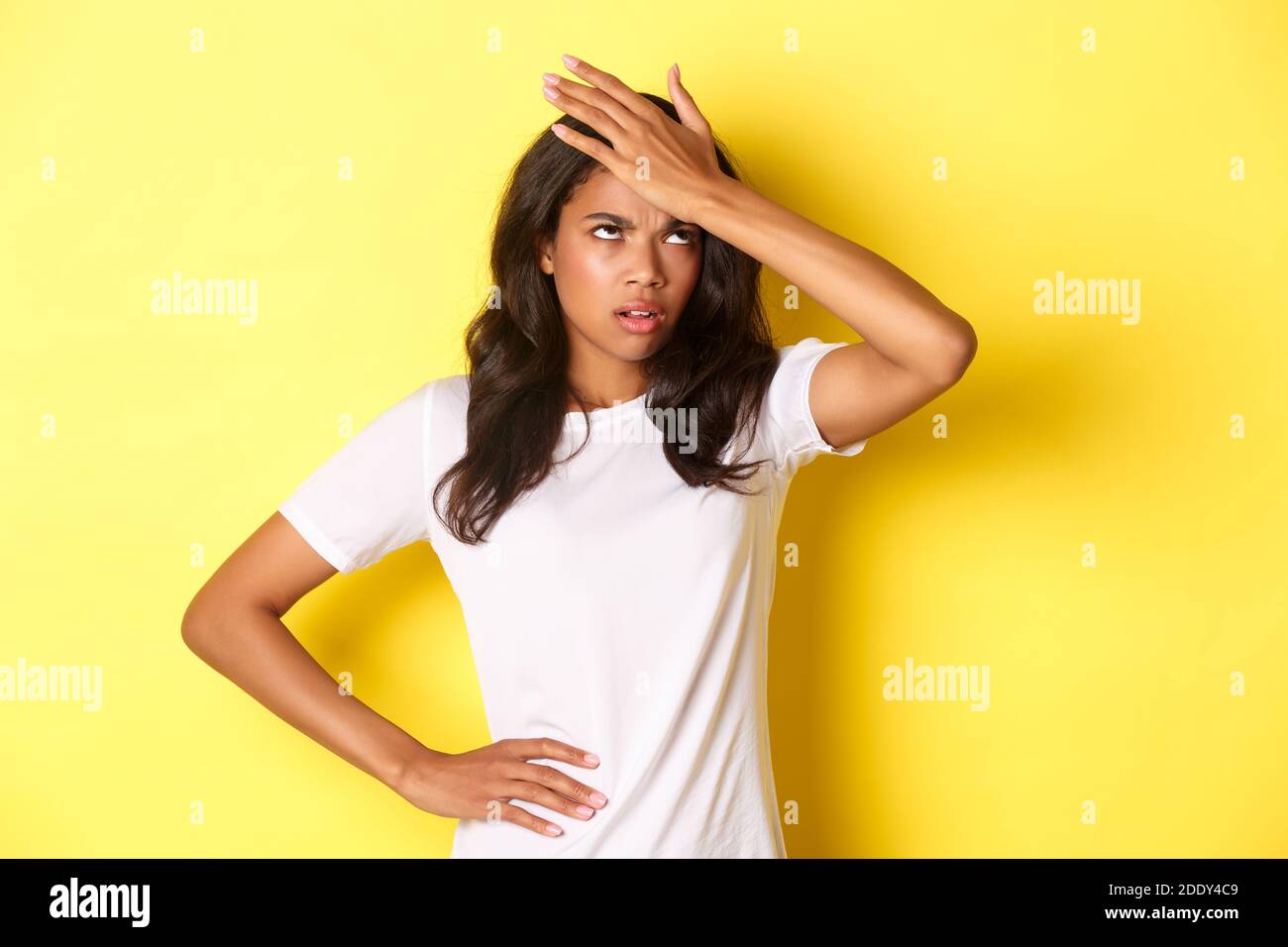 Porträt von verärgerten afroamerikanischen Mädchen, schlagen Stirn und Rollen ihre Augen gestört, vergessen etwas wichtiges, stand über gelbem Hintergrund Stockfoto