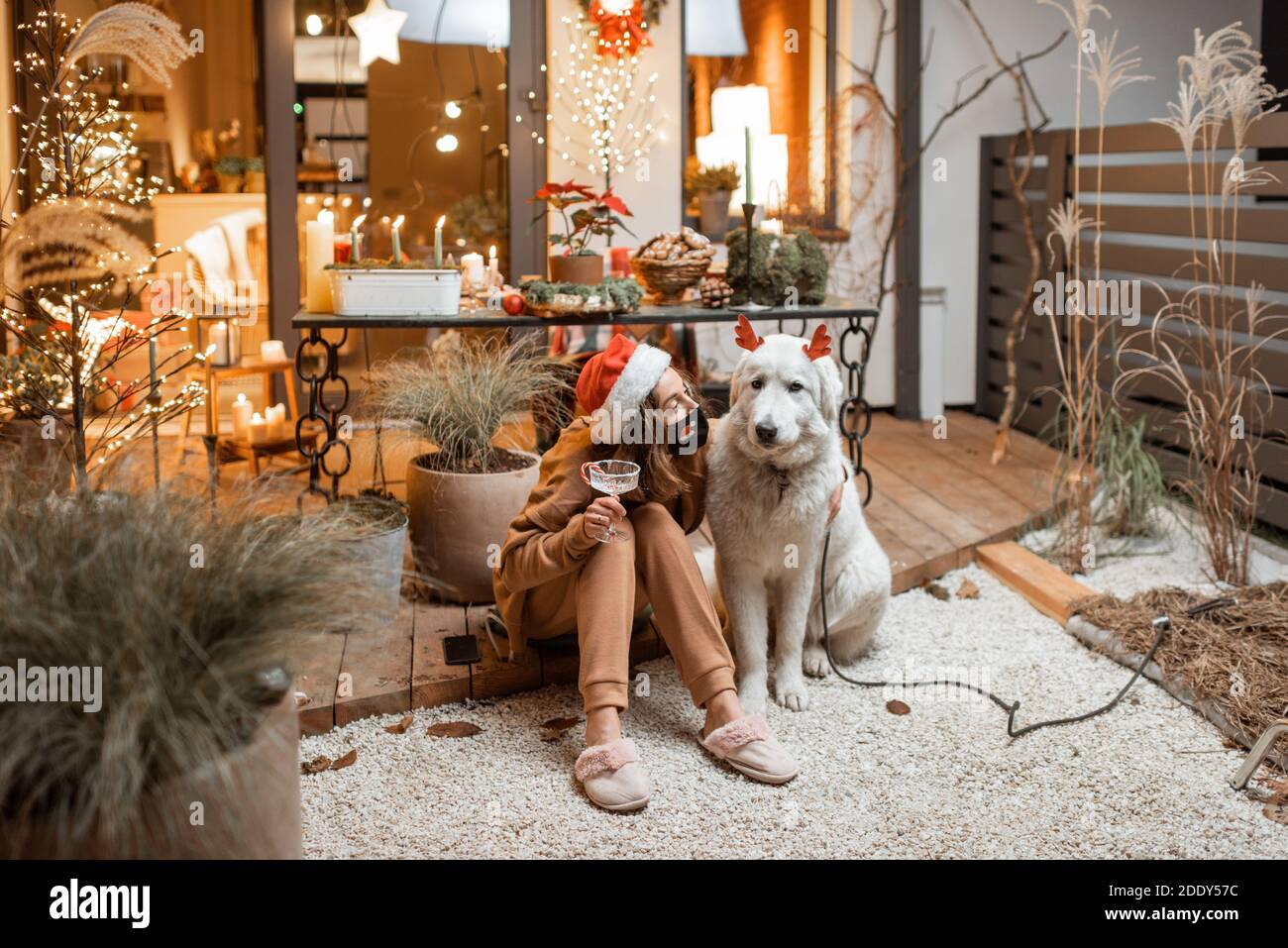 Junge Frau in Gesichtsmaske feiert mit einem Hund Neujahr Urlaub zu Hause. Konzept der Quarantäne und Selbstisolation während der Epidemie an Feiertagen Stockfoto