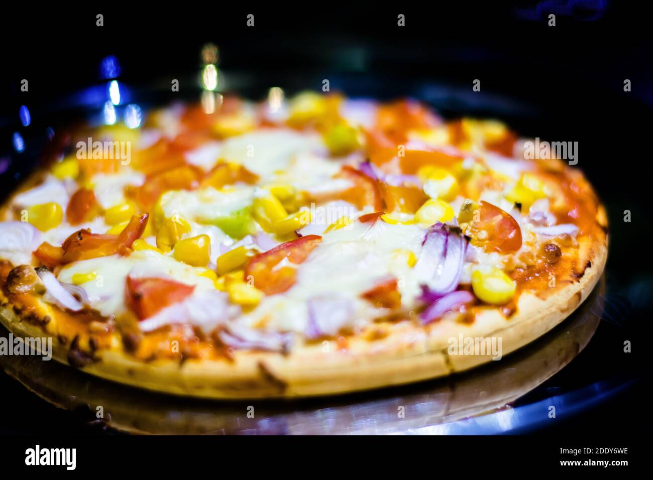 Frische hausgemachte Käse-Pizza, mit Tomaten, Zwiebeln, Mais Toppings, mit selektivem Fokus in Lockdown. Stockfoto
