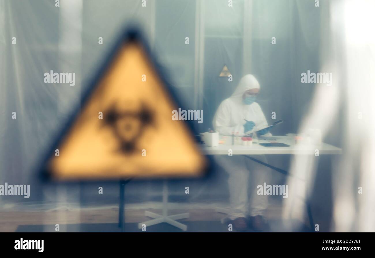 Wissenschaftlerinnen mit bakteriologischem Schutzanzug untersuchen im Labor hinter einem Schutzvorhang. Selektiver Fokus auf Wissenschaftler im Bac Stockfoto