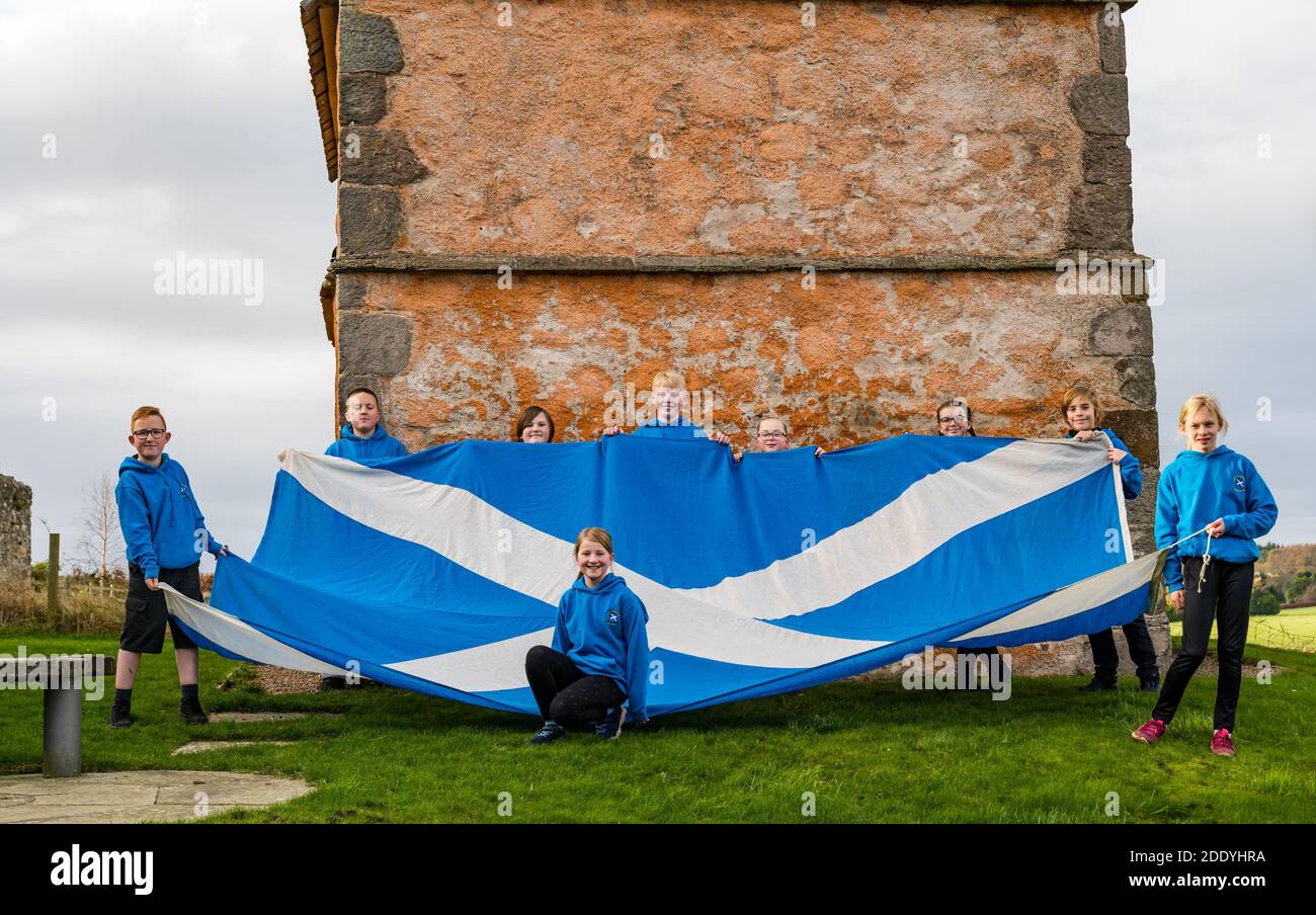 Athelstaneford, East Lothian, Schottland, Großbritannien, 27. November 2020. Saltyre Festival: Der Geburtsort der schottischen Nationalflagge zur Feier des Saltyre Festivals, das bis zum St. Andrew’s Day führt. Kinder der Grundschule in Athelstaneford feiern ihre Verbindung zum National Flag Heritage Centre mit P7-Kindern, die eine riesige Saltire-Flagge halten Stockfoto