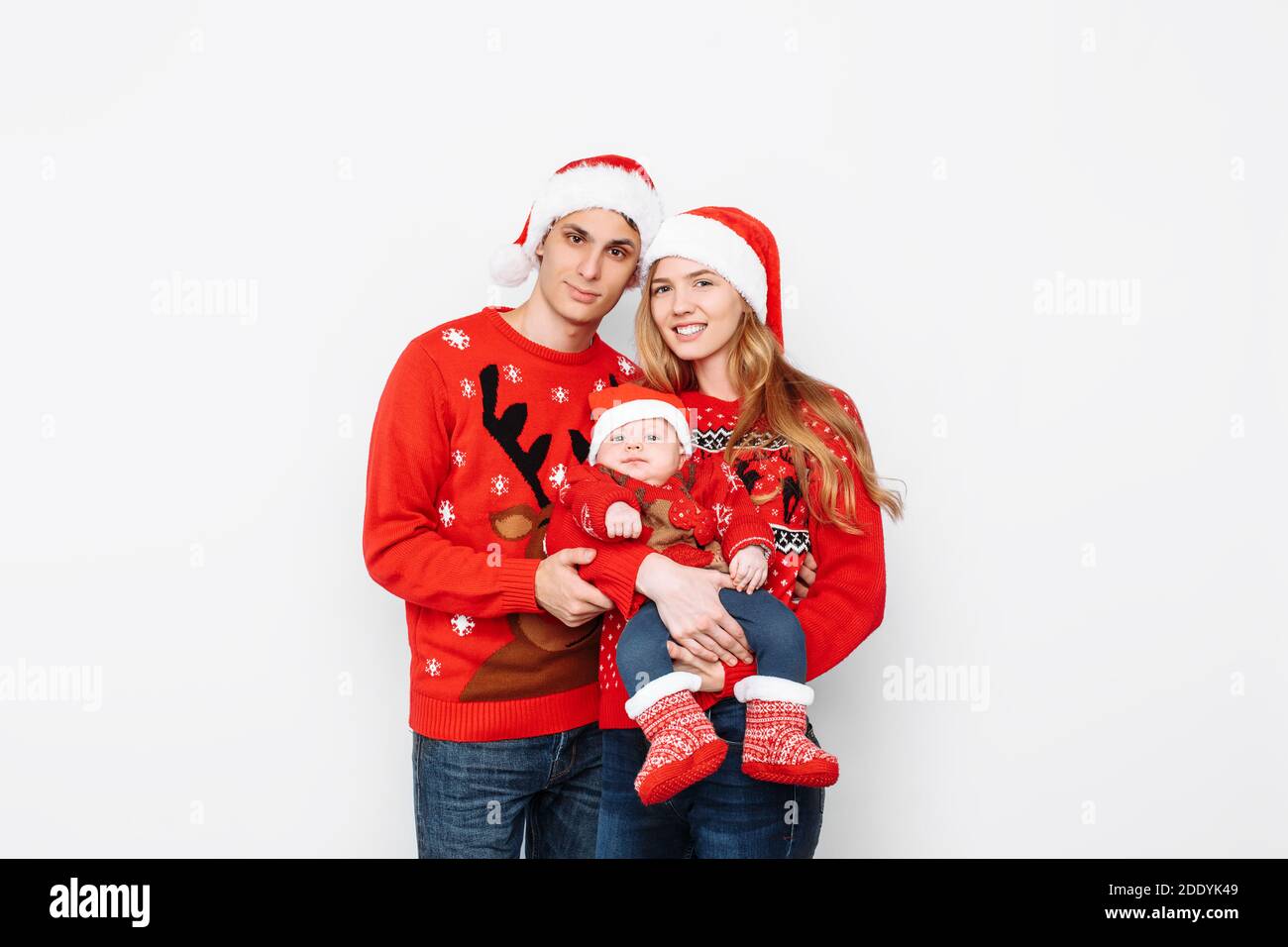 Glückliche Familie in weihnachtsmützen und weihnachtspullover, Mama Papa  und kleines Baby feiern Neujahr, auf weißem Hintergrund Stockfotografie -  Alamy