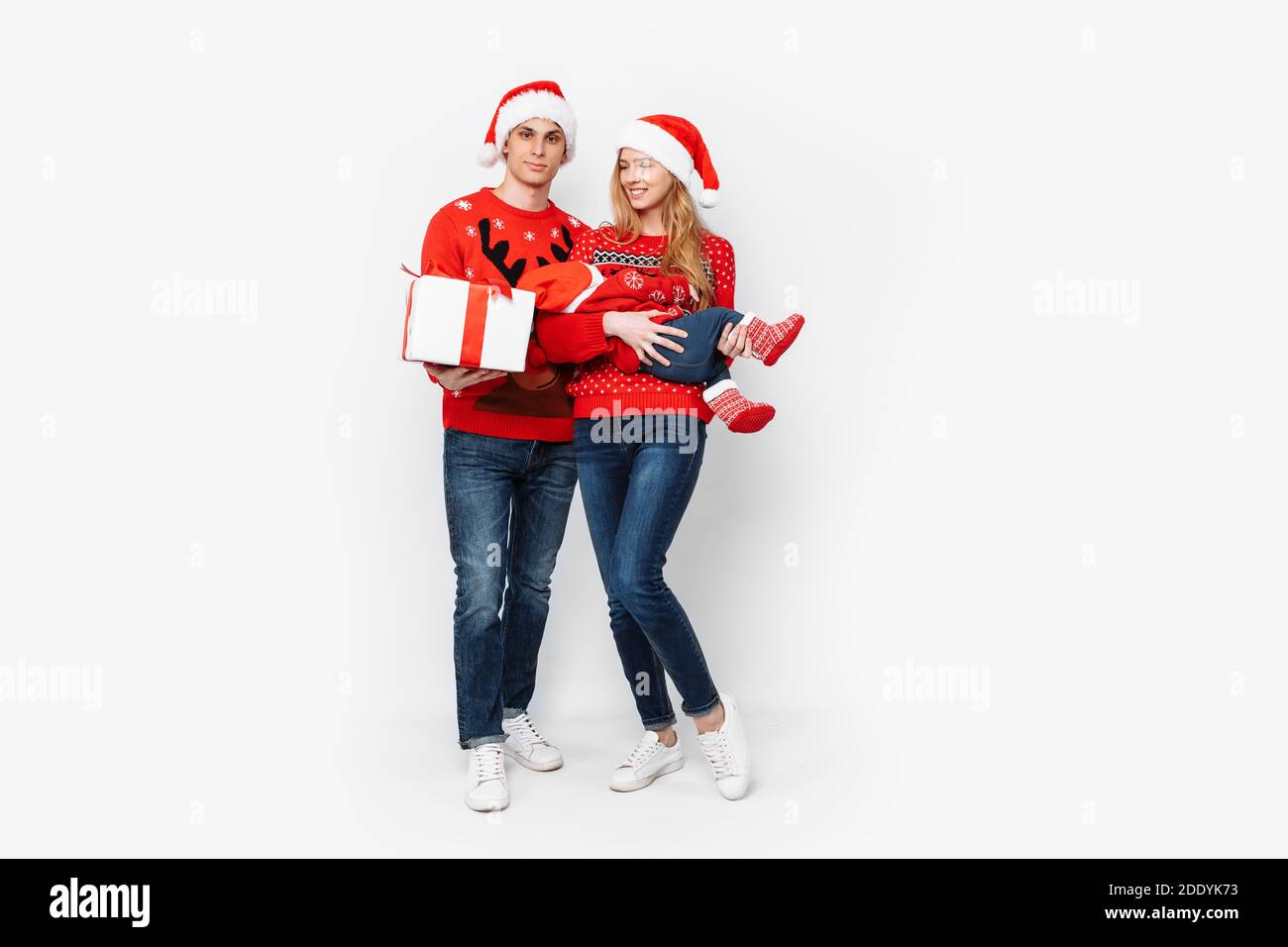 Glückliche Familie in weihnachtsmützen und weihnachtspullover, Mama Papa  und kleines Baby feiern Neujahr, auf weißem Hintergrund Stockfotografie -  Alamy