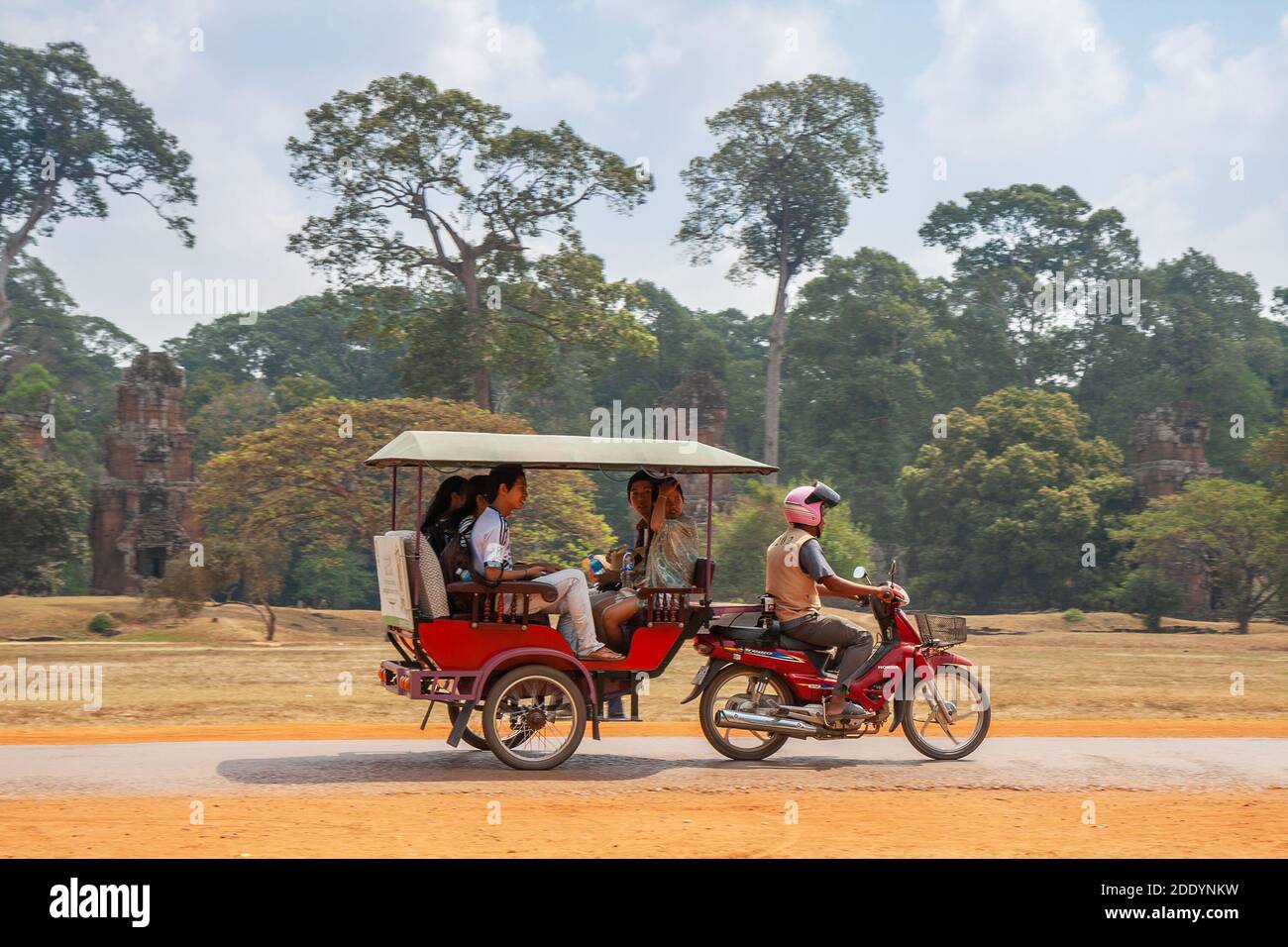 SIEM REAP, KAMBODSCHA - FEBRUAR 2013: Rikscha Tuk-Tuk mit asiatischen Touristen auf dem Weg zum Angkor Thom Tempel, Kambodscha Stockfoto