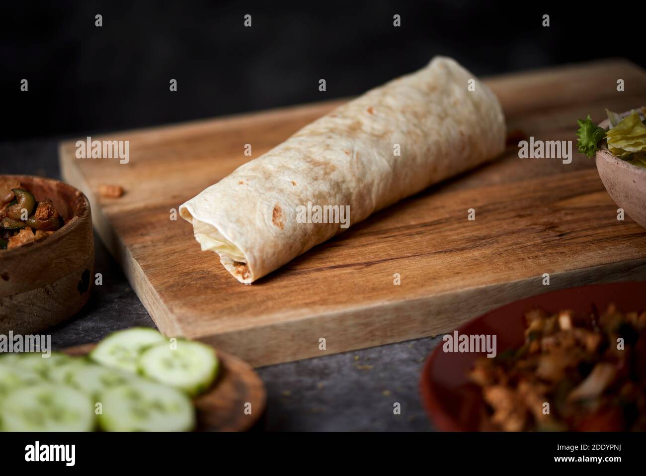 Nahaufnahme eines Durums oder Burritos, gefüllt mit Hühnerfleisch, das mit verschiedenen Gemüsesorten wie Zwiebeln oder rotem und grünem Pfeffer gekocht wird, und frischem Salat Stockfoto
