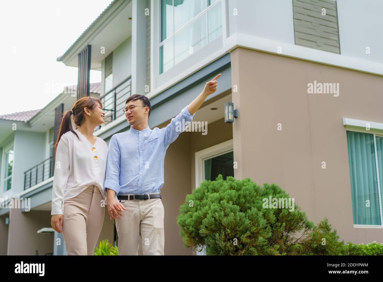 Portrait des asiatischen Paares, das gemeinsam umarmt und vor ihrem neuen Haus glücklich schaut, um neues Leben zu beginnen. Familie, Alter, Haus, Immobilien und Stockfoto