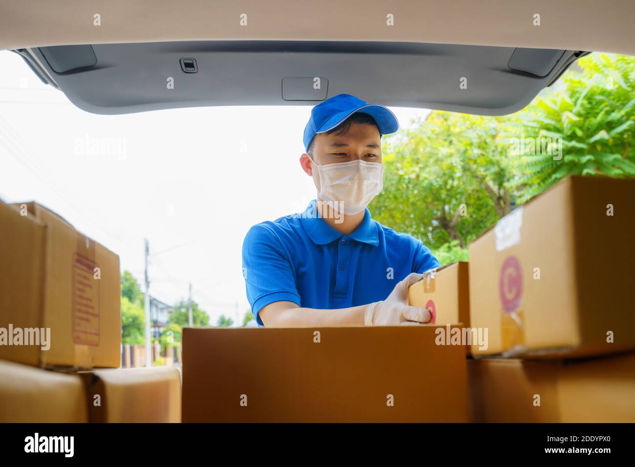 Asian Delivery man Services Kurier arbeitet mit Kartons auf van während der Coronavirus (COVID-19) Pandemie, Kurier trägt medizinische Maske und l Stockfoto