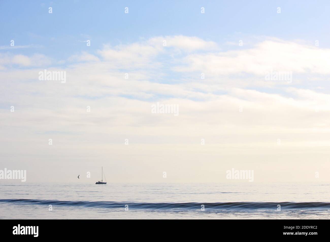 Ein Foto von einer Seenlandschaft mit einer Yacht in der Weite Entfernung am Horizont Stockfoto