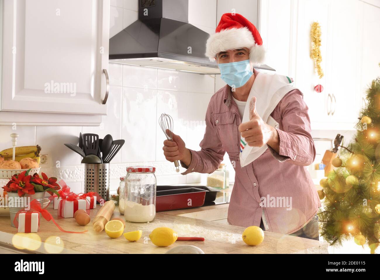 Mann kocht Desserts zu Hause mit einer Maske für covid-19 an den weihnachtsferien. Horizontale Zusammensetzung. Stockfoto