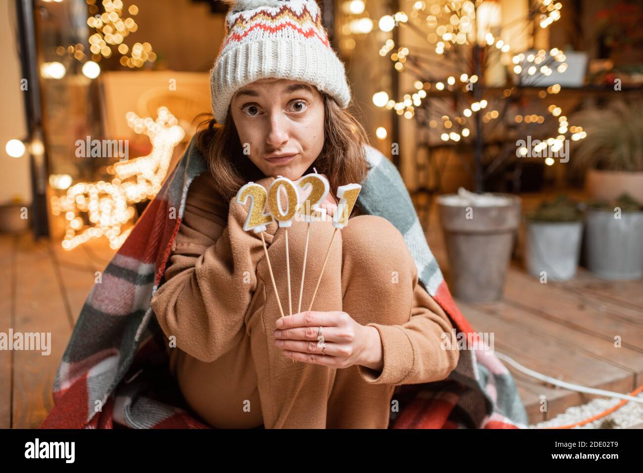 Porträt einer traurigen Frau in Gesichtsmaske feiern allein Neujahr. Kerzen halten 2021 mit der Hoffnung, dass die Quarantäne endet Stockfoto