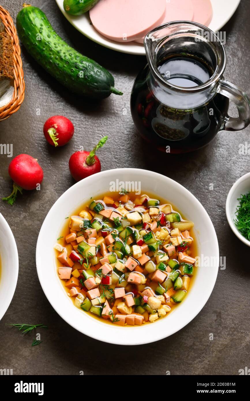 Traditionelle kalte russische Suppe Okroshka mit Wurst, Gemüse und Kvass auf braunem Stein Hintergrund. Leckeres Sommergericht zum Abendessen. Stockfoto