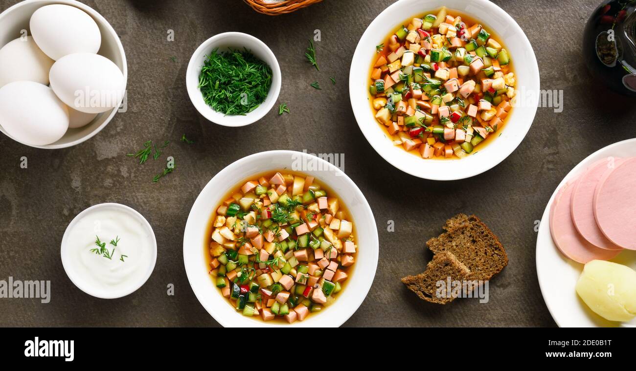 Kalte russische Suppe Okroshka mit Wurst, Gemüse und Kvass auf braunem Steingrund. Leckeres Sommergericht zum Abendessen. Draufsicht, flach liegend Stockfoto