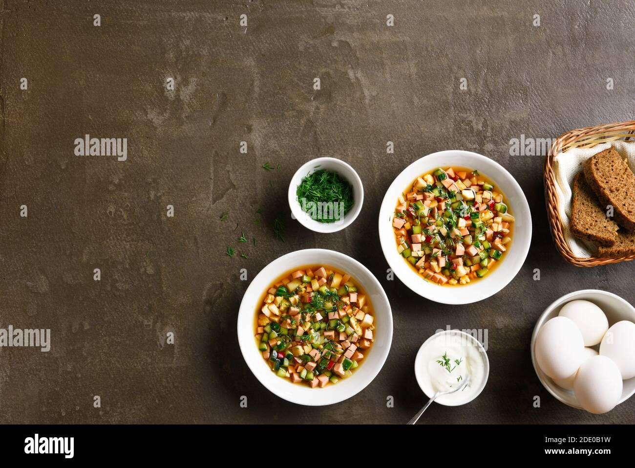 Sommer kalte russische Suppe Okroshka mit Wurst, Gemüse und Kvass über braunen Stein Hintergrund mit freiem Text Raum. Draufsicht, flaches Lay Stockfoto