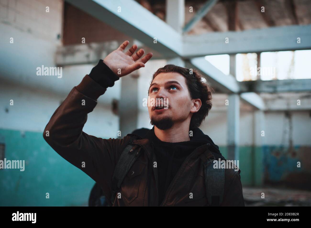 Lockiger junger Mann macht einen Plan des verlassenen Gebäudes Stockfoto