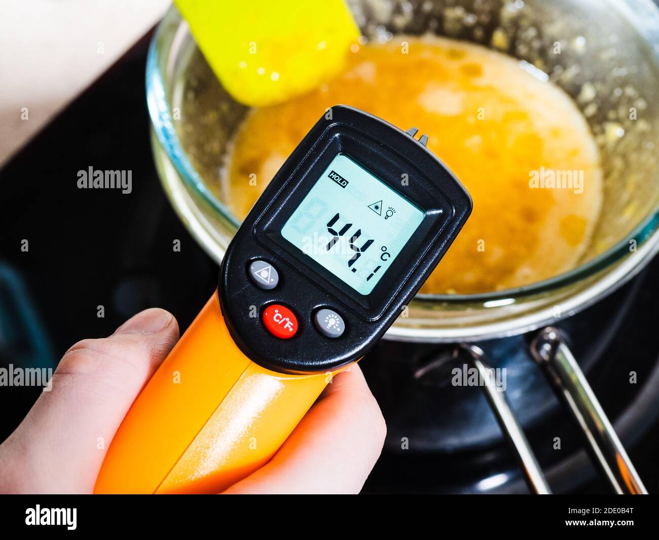 Kochen süßer Biskuitkuchen zu Hause - Messung der Temperatur von  Lebensmittel in Glasschale auf Wasserbad mit Infrarot-Thermometer Auf Herd  in der heimischen Küche Stockfotografie - Alamy