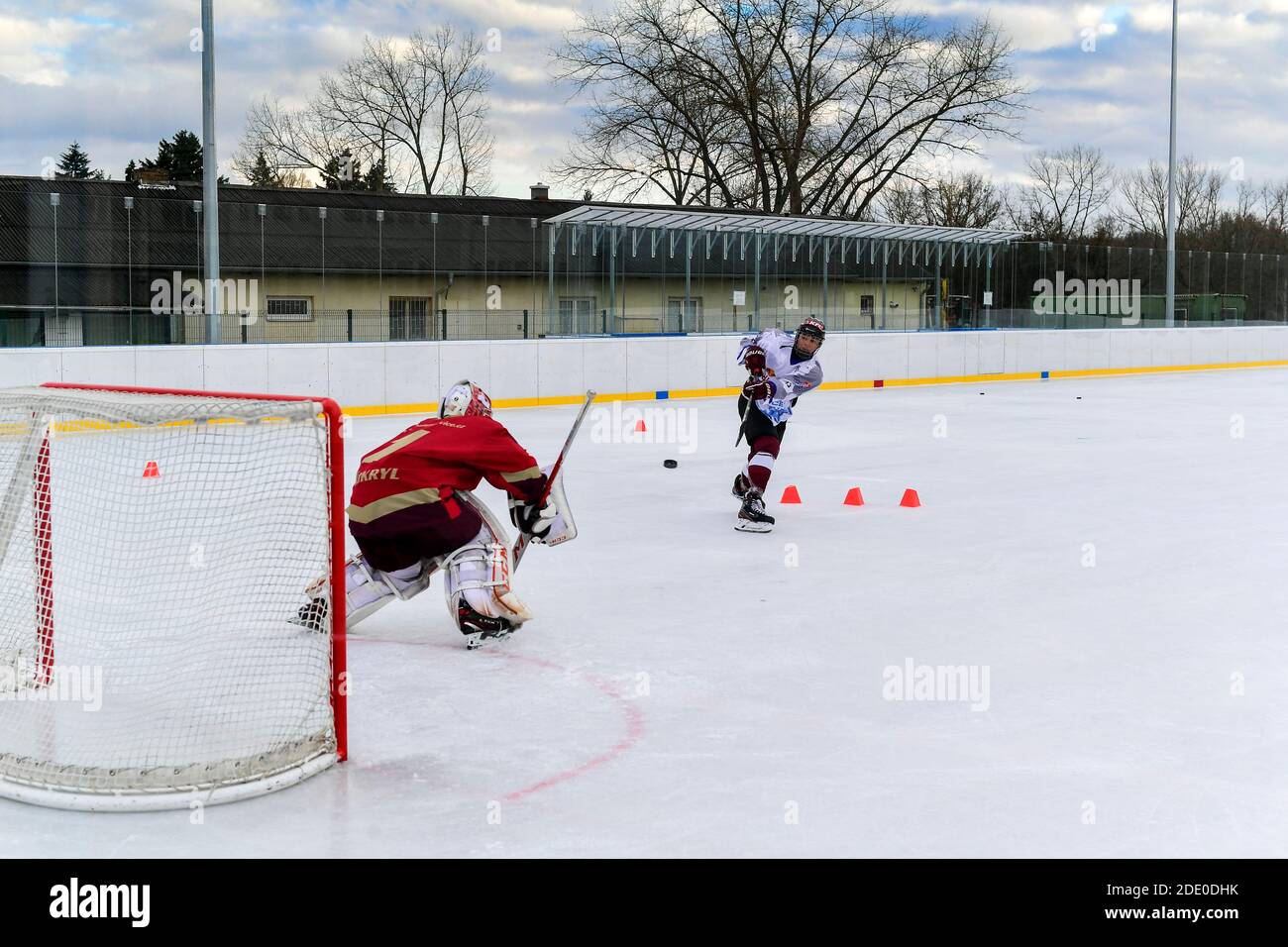 Jugendhockeyspieler Schüsse auf Torwart während Open-Air-Eishockey Schulung Stockfoto