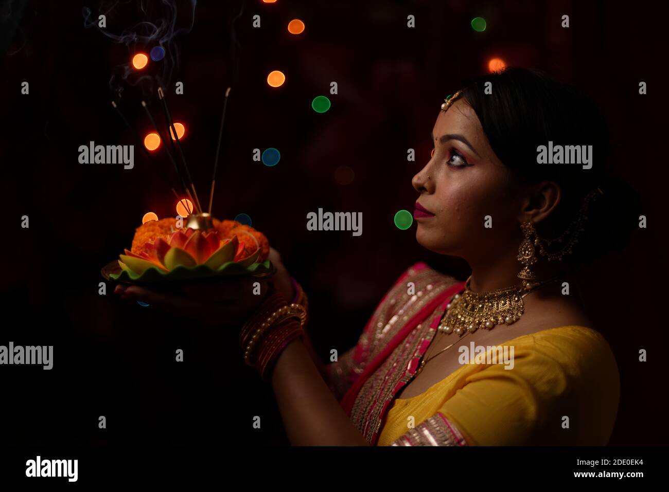 Eine indische Bengali schöne Brünette Frau verehrt vor dem bunten Licht Bokeh Hintergrund am Abend von Diwali. Indischer Lebensstil. Stockfoto