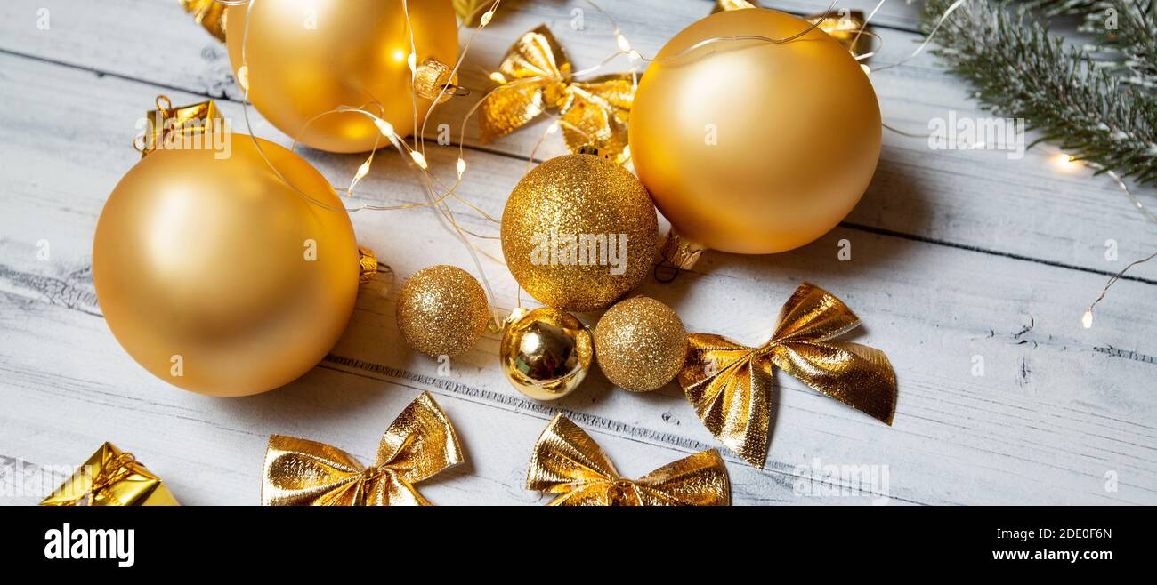 goldene Weihnachts-Spielzeug auf einem hellen Holzhintergrund. Banner Stockfoto