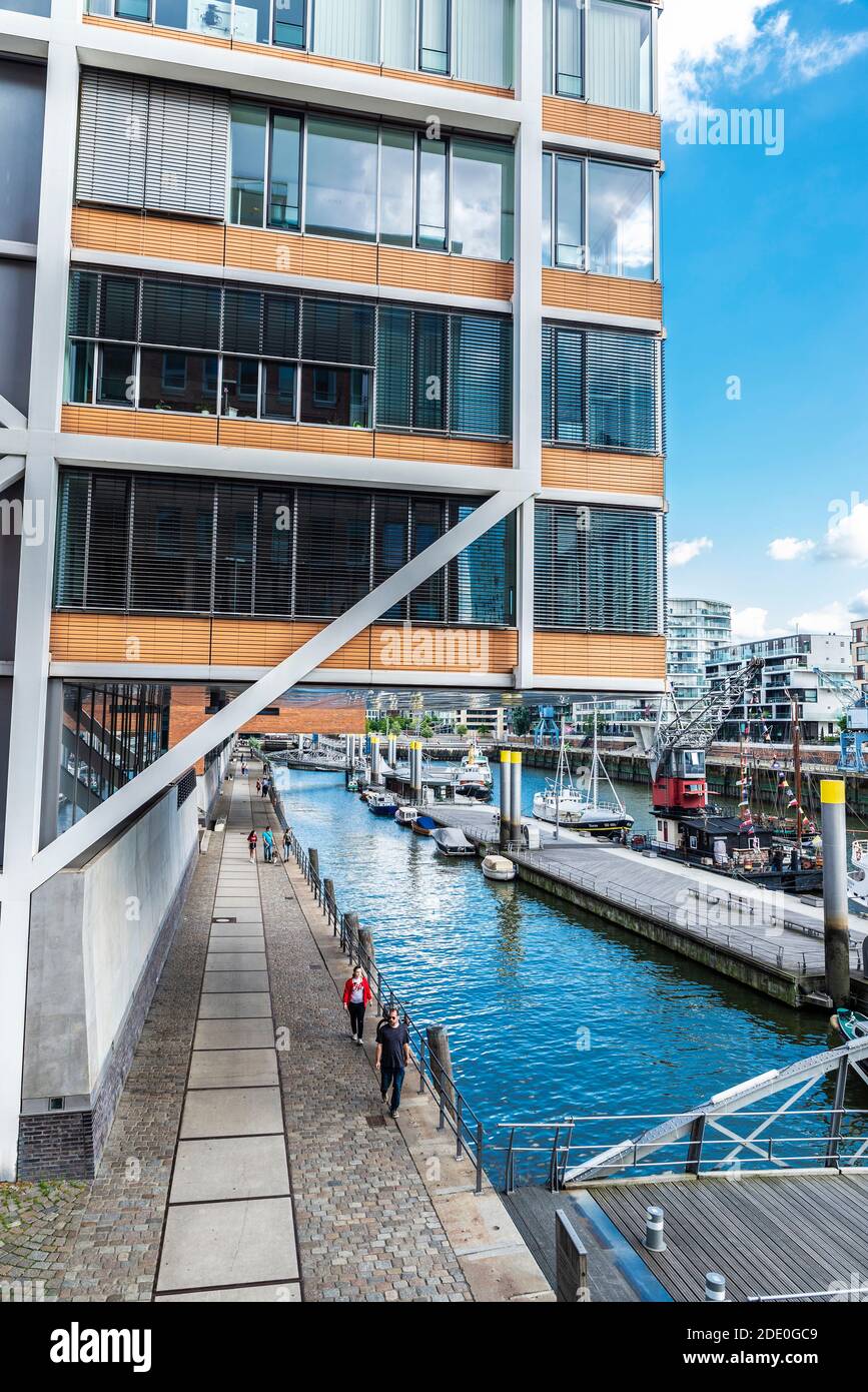 Hamburg, 21. August 2019: Moderne Gebäude und eine Anlegestelle mit Booten und Menschen in der Nähe eines Kanals im Stadtteil HafenCity, Hamburg Stockfoto