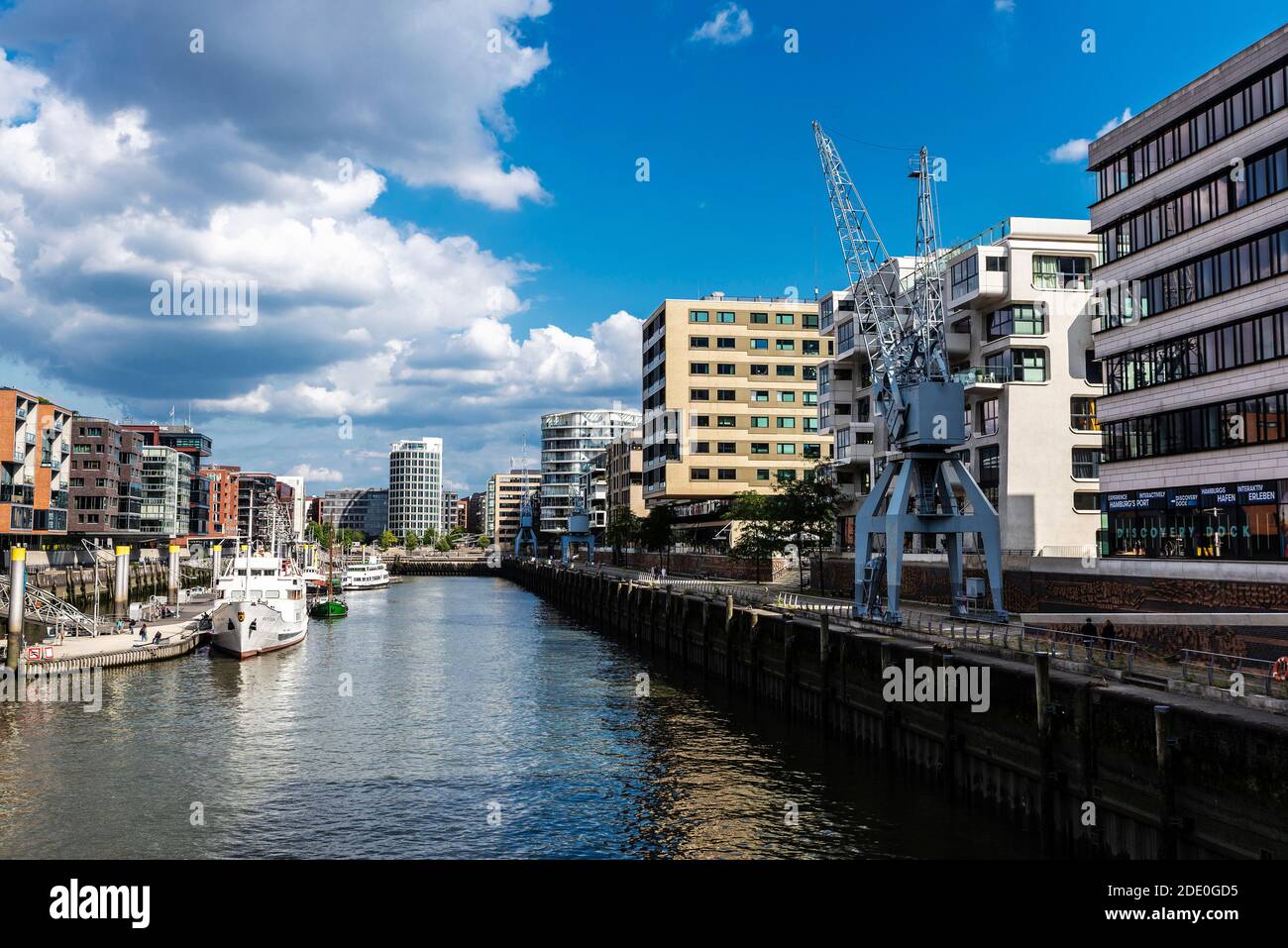 Hamburg, Deutschland - 21. August 2019: Moderne Gebäude und eine Anlegestelle mit Booten, Kräne und Menschen in der HafenCity, Hamburg, Deutschland Stockfoto