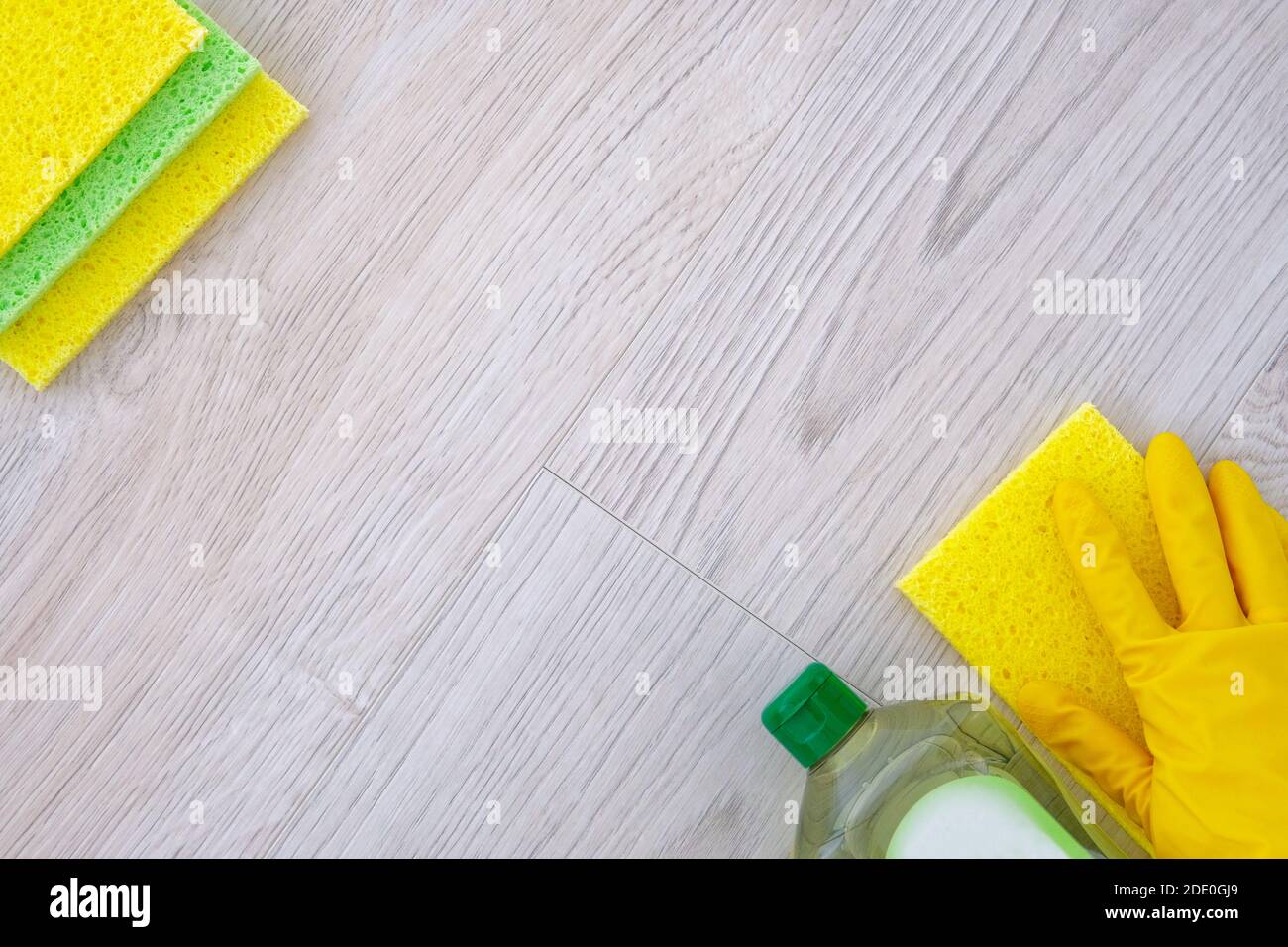Reinigungsdienstkonzept. Hand in gelben Gummi-Schutzhandschuh mit Mikrofasertuch. Flache Reinigungsprodukte, Kopierplatz. Stockfoto