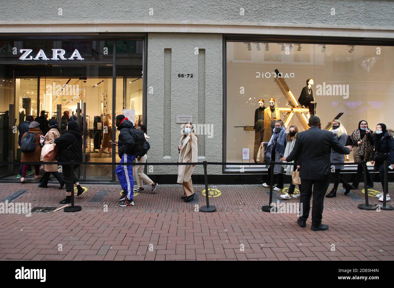 Ein Wachmann führt die Verbraucher in der Schlange zu tragen Schützende  Gesichtsmasken, um den Zara-Speicher während "Black Freitag' auf der  Einkaufsstraße Kalve Stockfotografie - Alamy