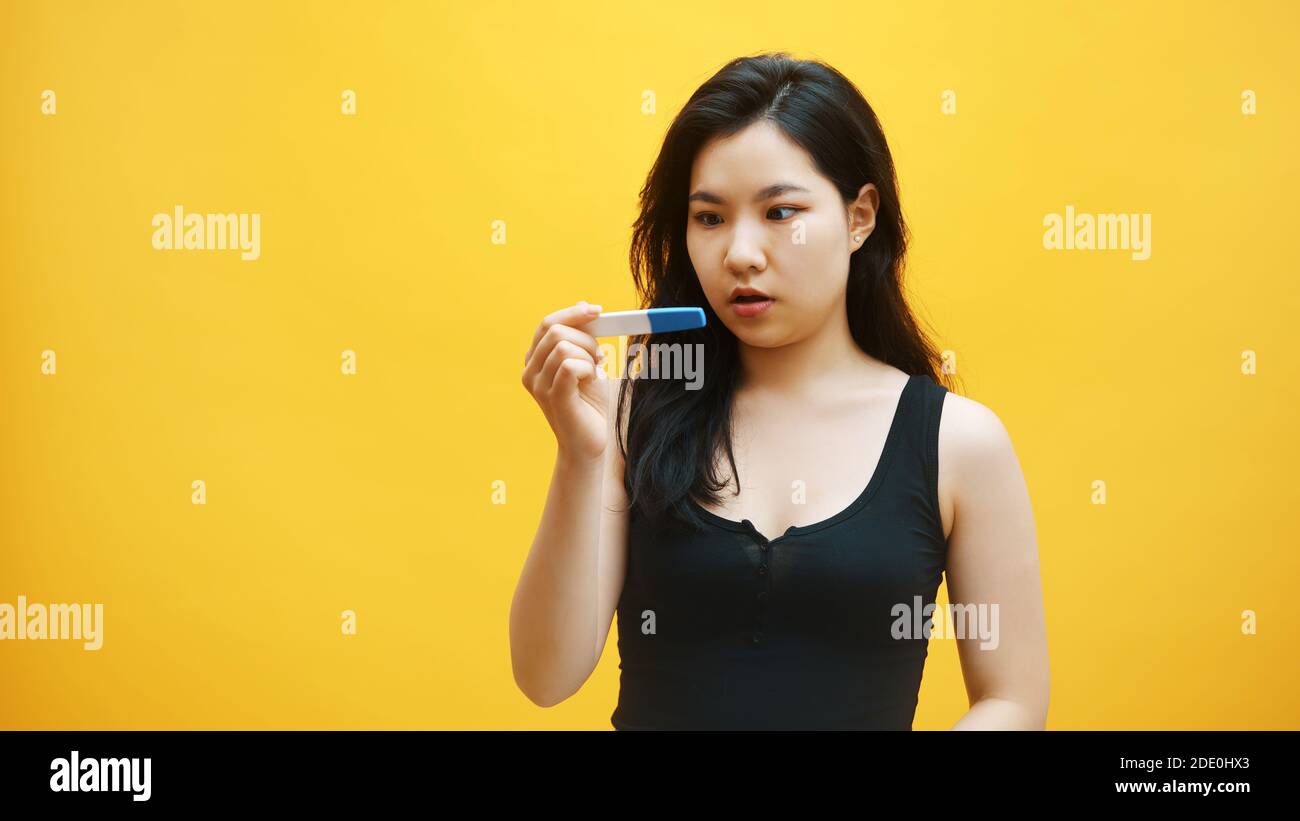 Ungewollte Schwangerschaft Konzept. Ungeduldig junge asiatische Frau Blick auf die Schwangerschaft Test warten auf Ergebnisse. . Hochwertige Fotos Stockfoto