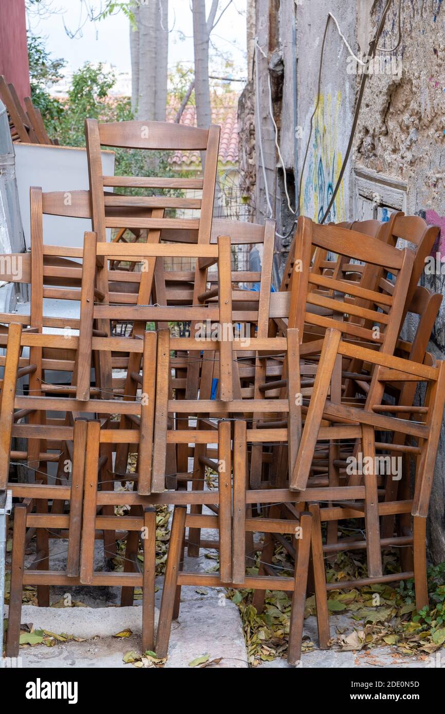 Stühle stapeln, geschlossenes Restaurant Covid-19 Pandemic Lockdown. Hölzerne Taverne Sitze im Freien gestapelt, vertikal. Monastiraki, Athen Griechenland Stockfoto
