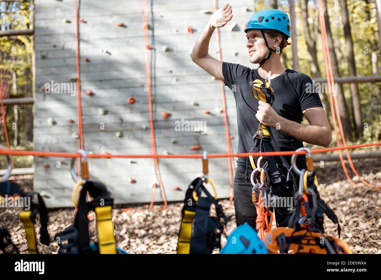 Gut aussehender Mann, gut ausgestattet mit schützender Kletterausrüstung, an der man steht Vergnügungspark im Freien Stockfoto