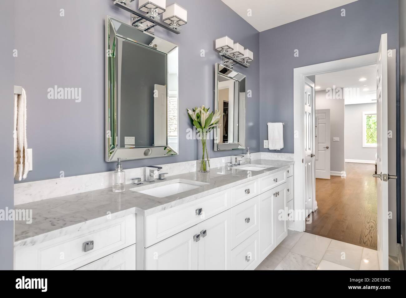 Ein luxuriöses Badezimmer mit lila Wänden, einem weißen Schrank und Arbeitsplatten, und Chrom Hardware Blick in Richtung der primären Schlafzimmer. Stockfoto