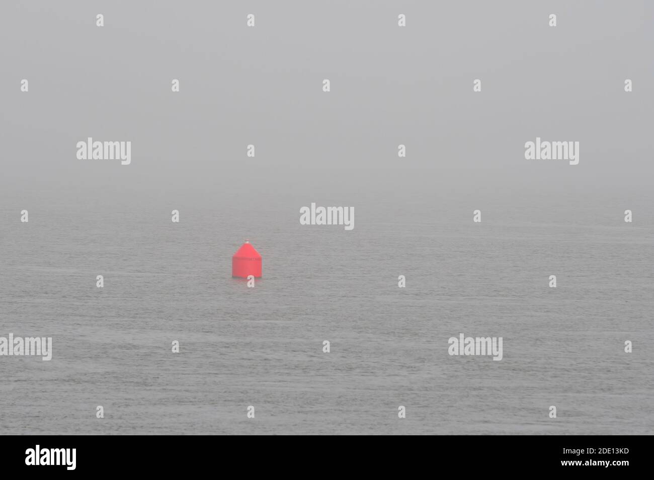 Eine kleine rote Navigationsboje in einem nebligen Ozean. Dies ist eine rote Boje. Das Meer ist ruhig und sehr neblig. Stockfoto