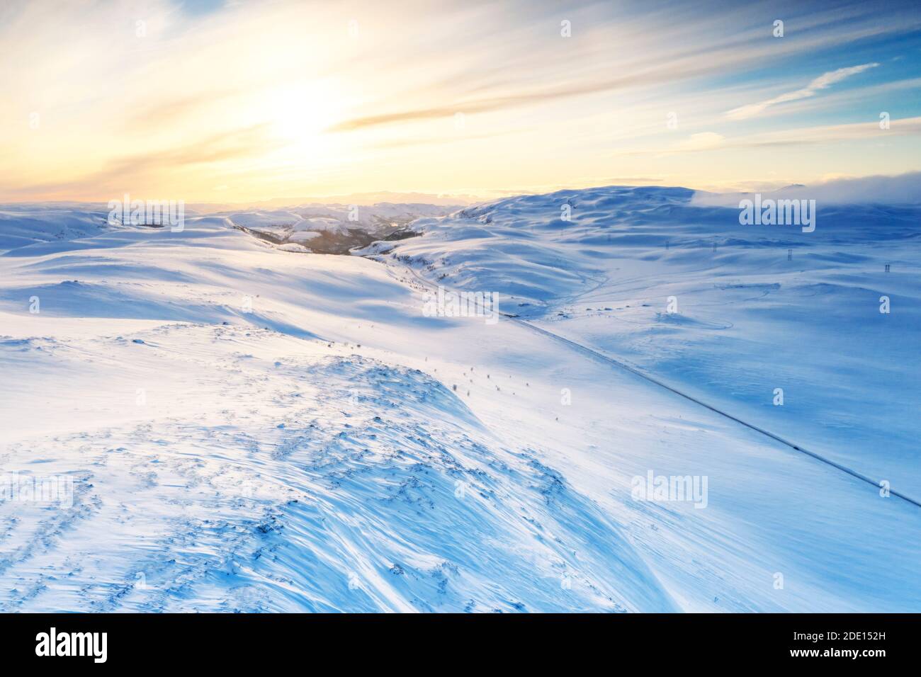 Luftaufnahme der leeren Straße über Berge mit Schnee bedeckt von Sonnenaufgang beleuchtet, Sennalandet, Alta, Troms Og Finnmark, Arktis, Norwegen Stockfoto