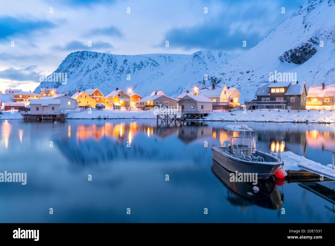 Das beleuchtete Dorf Sorvaer spiegelte sich im kalten Meer während der Winterdämmerung, Soroya Island, Troms Og Finnmark, Nordnorwegen, Skandinavien, Europa Stockfoto