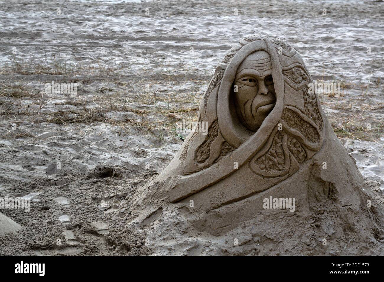 Die Sandskulptur des Gesichts, das im Leinen auf drapiert ist Ein Sandstrand Stockfoto