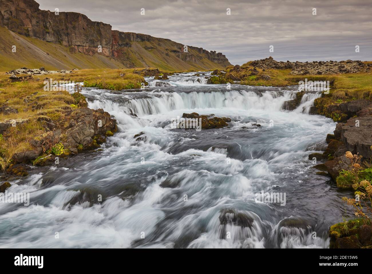 Eine klassische isländische Landschaft, ein Fluss fließt entlang der Basis einer Klippe, der Fossalar River, in der Nähe von Kirkjubaejarklaustur, Island, Polarregionen Stockfoto