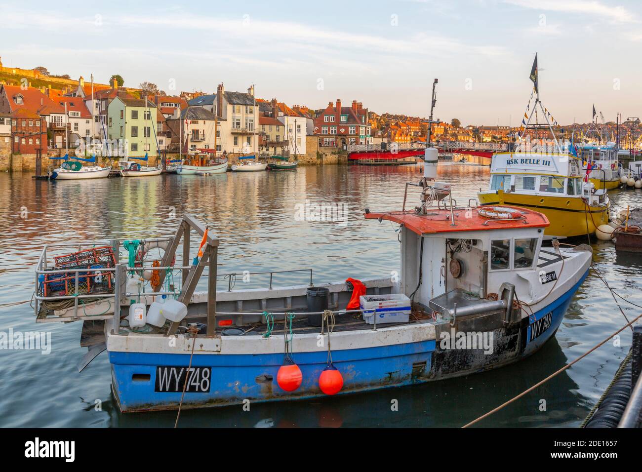 Blick auf die Häuser am Flussufer und Fischerboote auf dem Fluss Esk bei Sonnenuntergang, Whitby, Yorkshire, England, Großbritannien, Europa Stockfoto