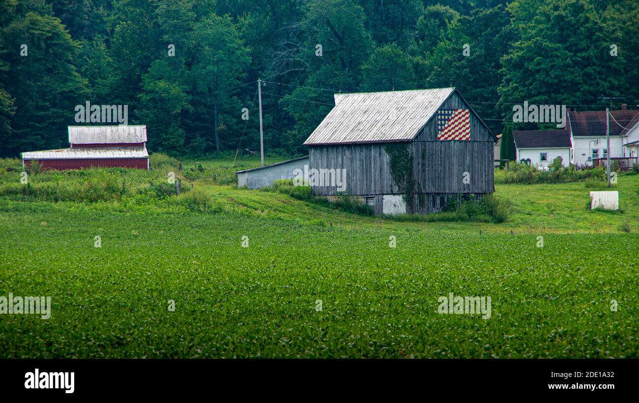 Indiana, USA--Aug 26, 2018; alte warn grauen Holzscheune im Feld mit amerikanischer Flagge auf sie gemalt Stockfoto