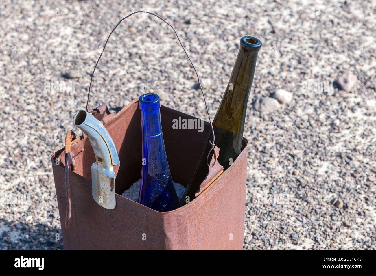 Verlassene Weinflaschen und ein Ölauslauf in einem rostigen Metallgehäuse Stockfoto