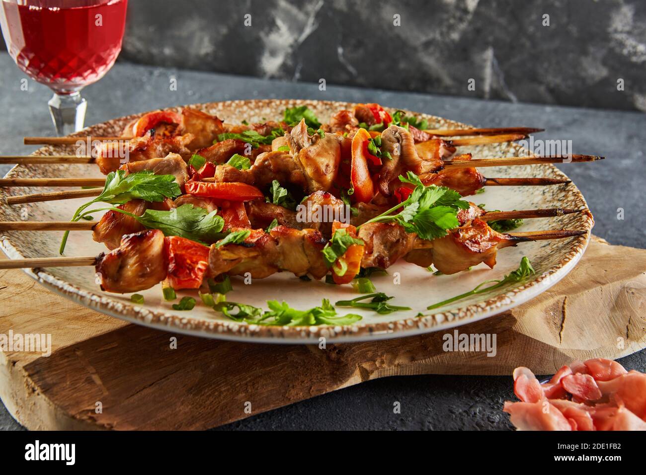 Japanischer Yakitori-Schaschlik auf einem Holzbrett mit einem Glas Rotwein und Ingwer. Platz für Text kopieren. Stockfoto