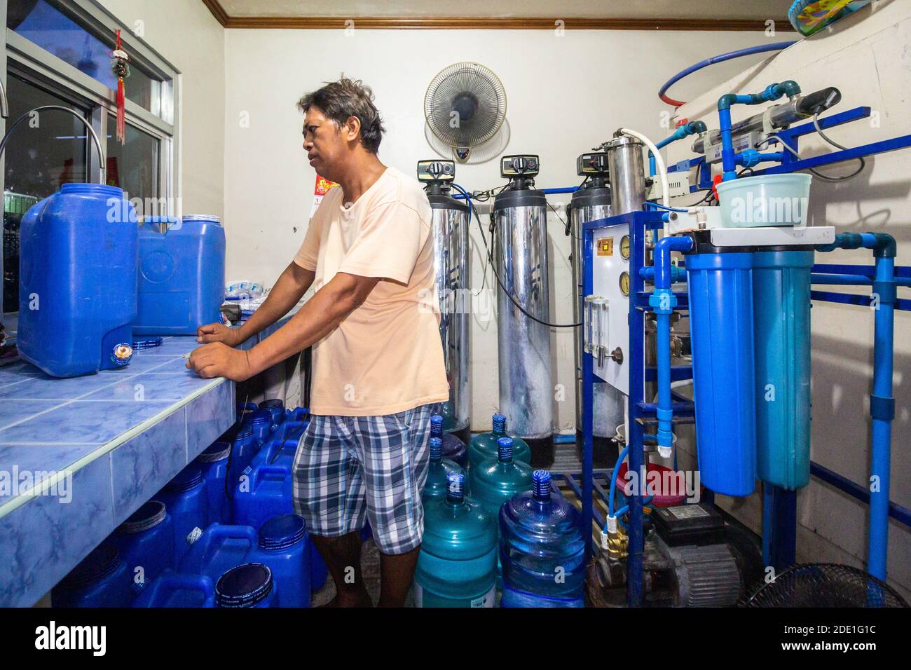 Ein Unternehmer, der Wasser auffüllt und Behälter für Kunden in Batangas, Philippinen, abfüllt Stockfoto