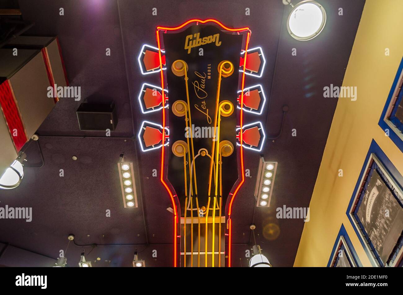 Giant Les Paul Gibson E-Gitarre Kopfteil in Hard Rock Cafe Innendekoration. Beleuchtete Neon Multicolored Lights & hängend von der Decke Stockfoto