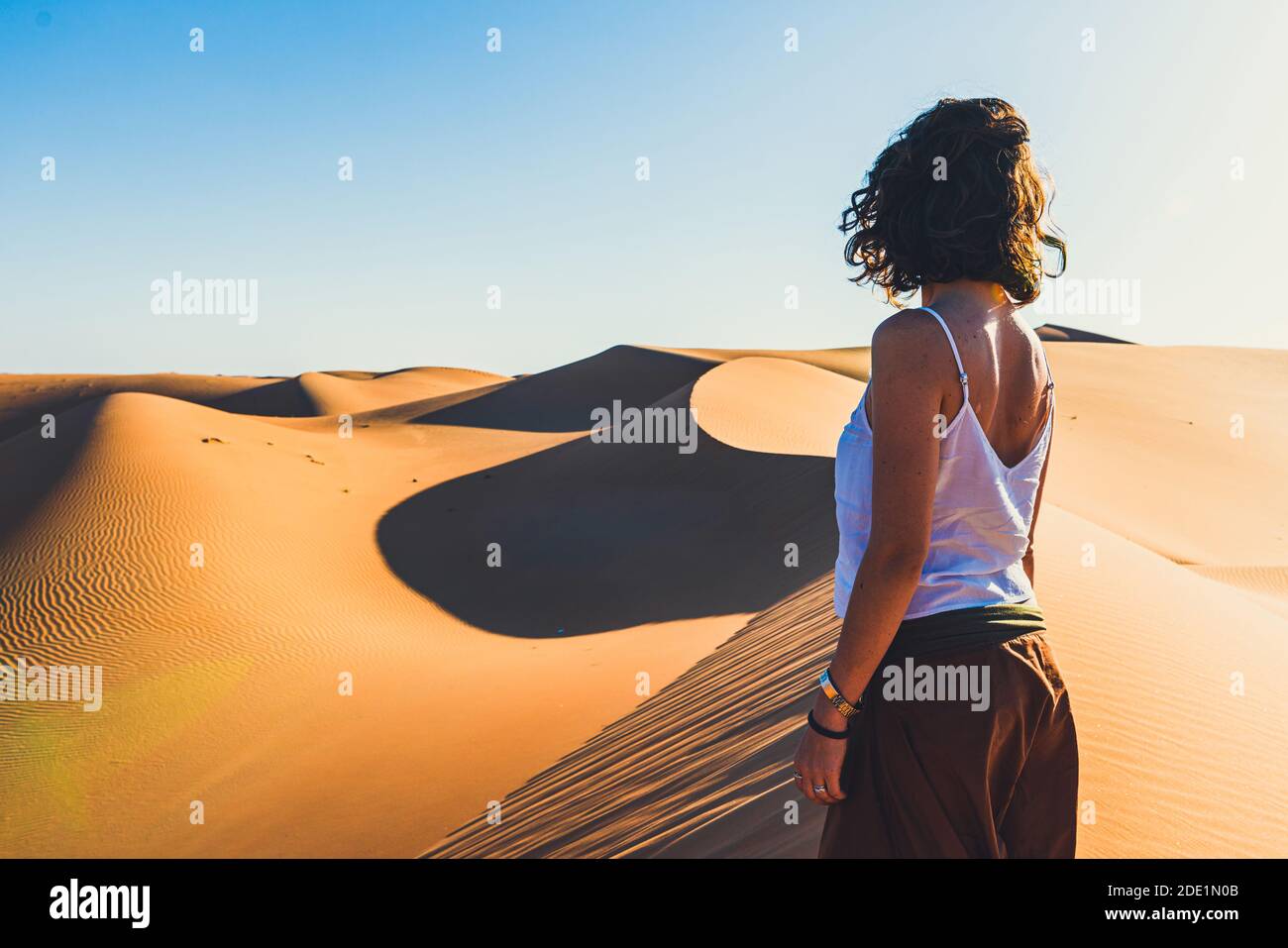 Hübsche Frau in weißem Hemd auf der Spitze der Düne stehen und blickt auf die weite Wüste, Ruhe Szene, Liwa Wüste VAE Stockfoto