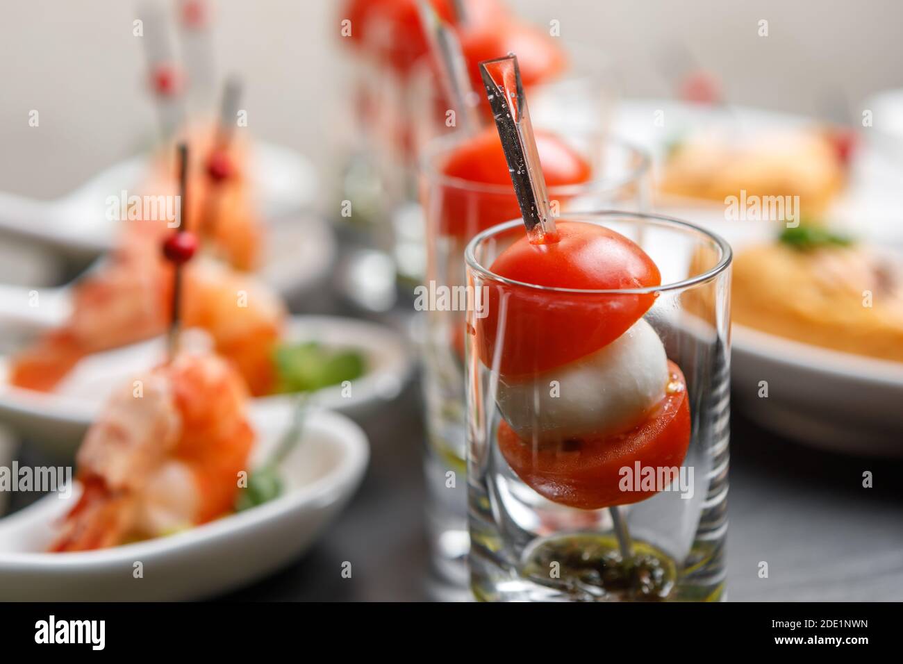 Kirschtomaten und Mozzarella Canapes auf Spieße in einem Glas Glas mit einem Hintergrund von Garnelen in Nahaufnahme Stockfoto