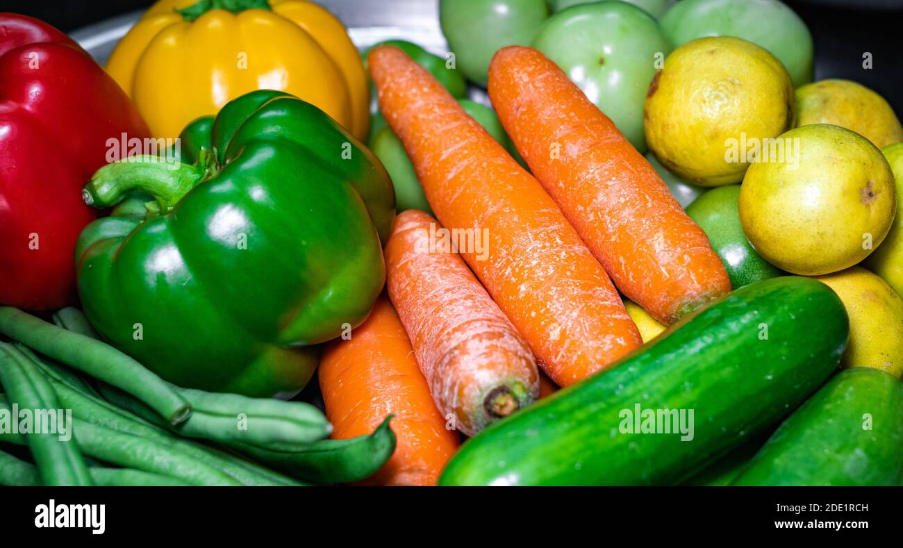 Selektive Konzentration von Karotten, grünem Paprika, Zitronen auf einem Teller mit verschiedenen Gemüsesorten Stockfoto