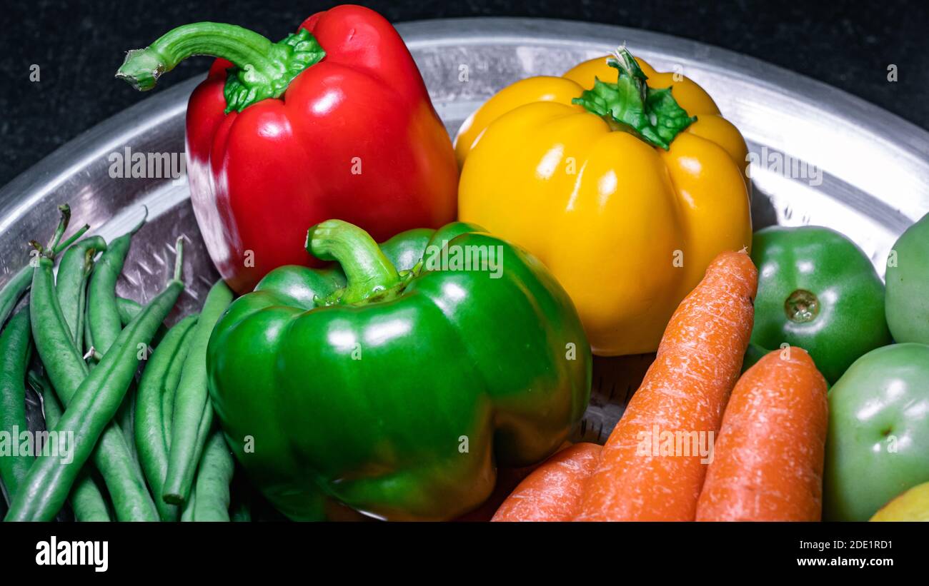 Nahaufnahme von grünem Paprika, rotem Paprika, gelbem Paprika auf einer Edelstahlplatte Stockfoto