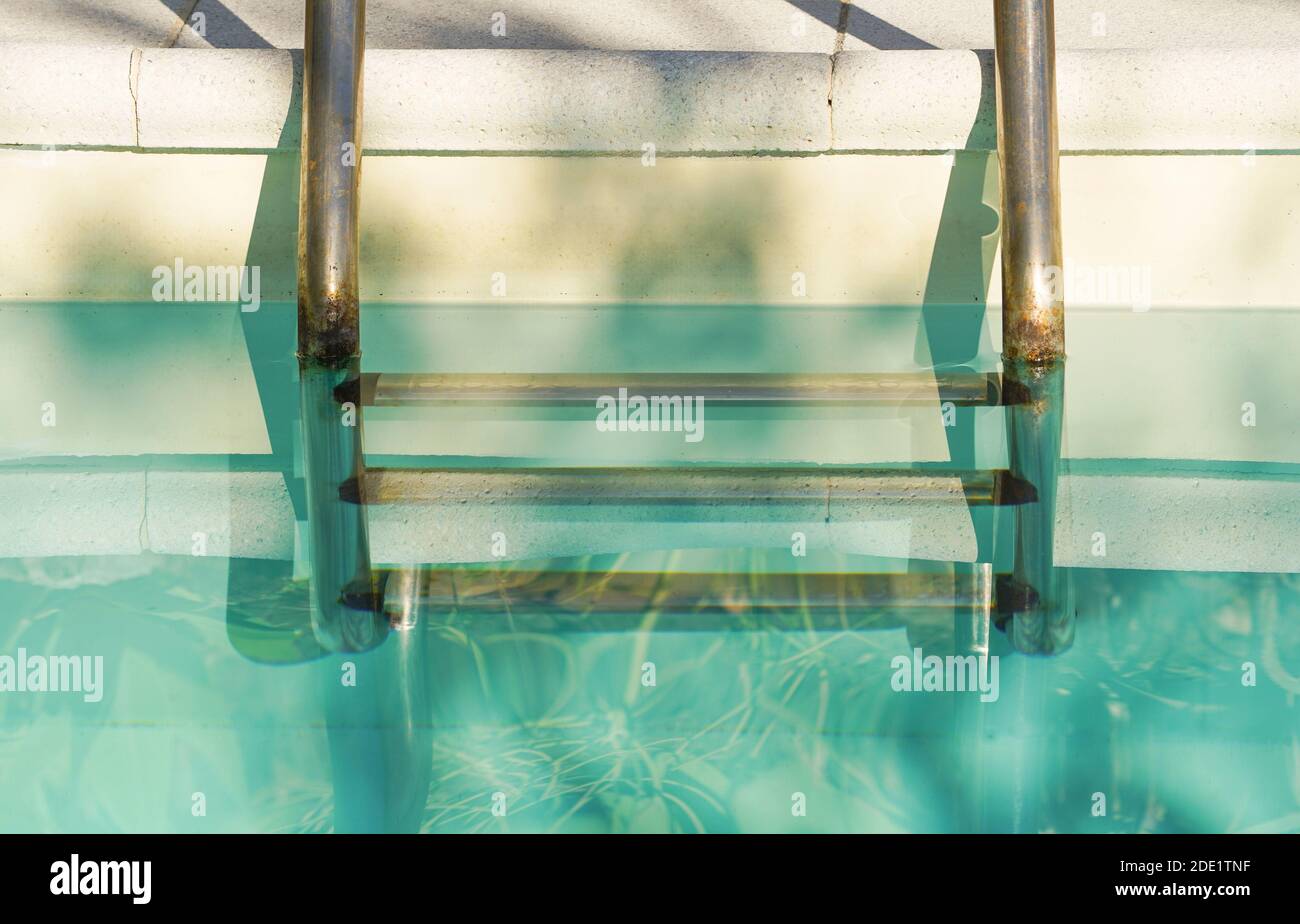 Detail eines Swimmingpools am Pool mit rostiger Metalltreppe. Spanien. Stockfoto