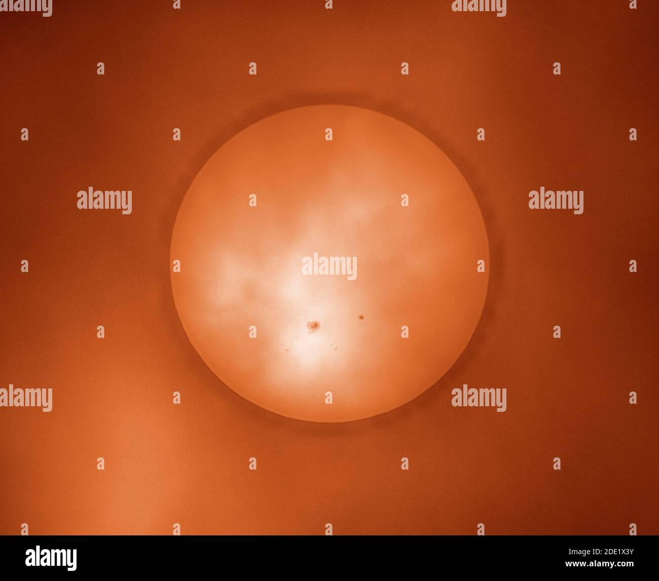 London, Großbritannien. 28. November 2020. Wolke und Nebel erzeugen einen Filter, durch den ein massiver Sonnenfleck auf einer wolkigen Sonne sichtbar ist. Dieser Sonnenfleck, AR2786, der größte seit Jahren und ein Vielfaches des Durchmessers des Planeten Erde, ist eine potenzielle Quelle für Sonneneruptionen der M-Klasse. Der kleinere Sonnentopf rechts ist AR2785. Dieses Bild wurde eingefärbt. Quelle: Malcolm Park/Alamy Live News. Stockfoto
