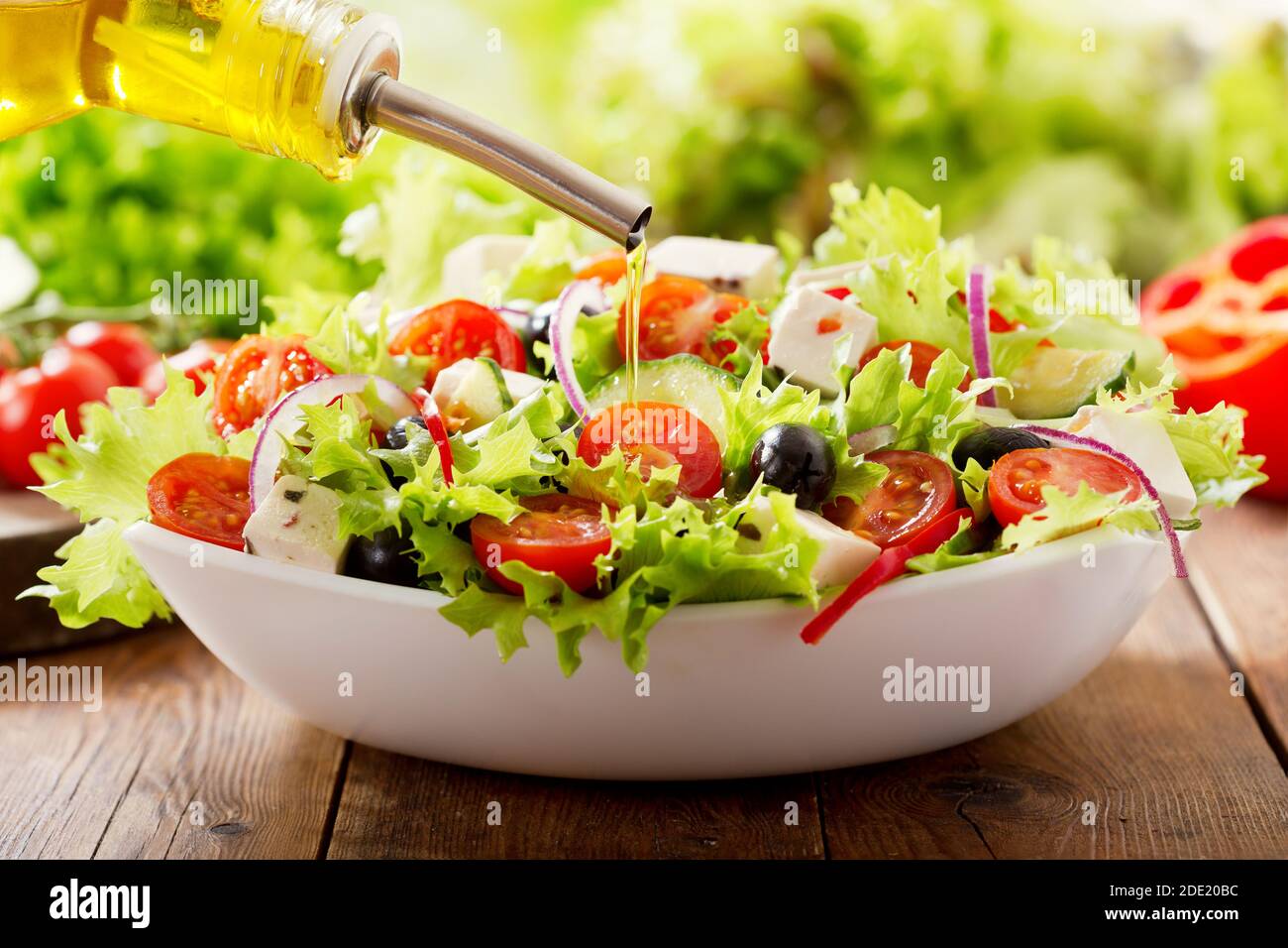 Kochen Salat. Olivenöl Gießen in Schüssel mit frischem Gemüsesalat Stockfoto